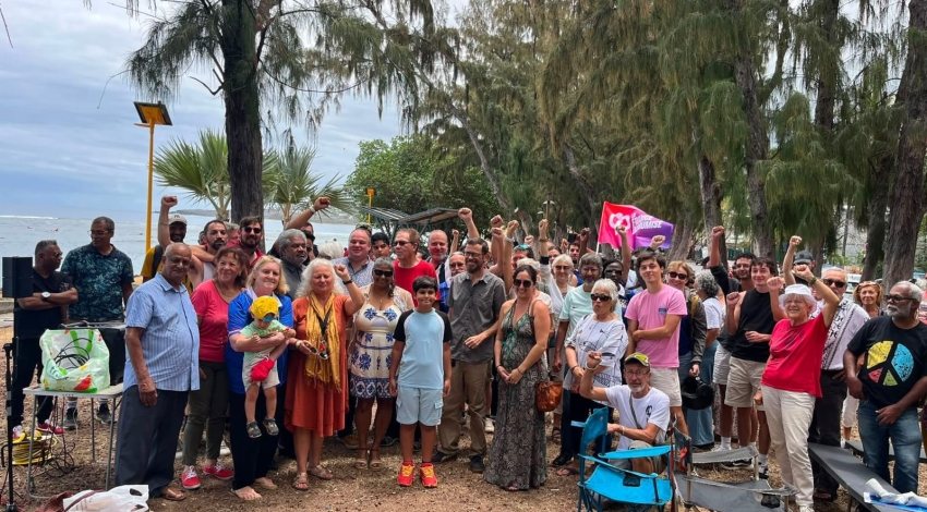 Rassemblement des sympathisants LFI en bord de mer à Saint-Leu, poings levés sous les filaos.